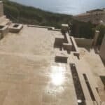 Beautiful outdoor patio with tile flooring and ocean view in the background.