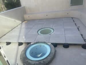 Newly installed gray tile flooring with a round hot tub on a balcony.