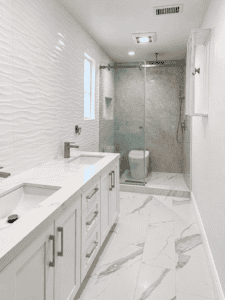 Elegant bathroom with white textured wall tiles and marble flooring.