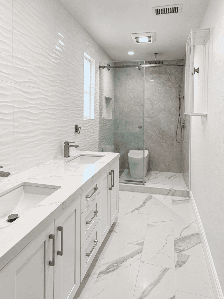 Elegant bathroom with white textured wall tiles and marble flooring.