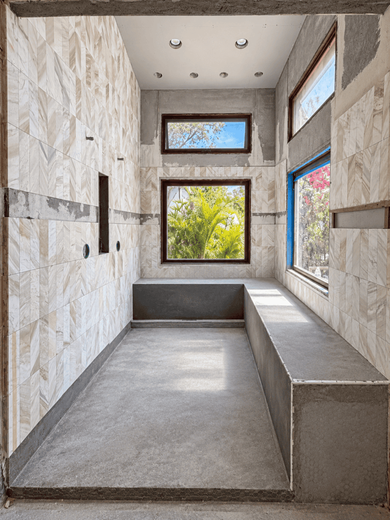 Interior of a modern room with tile walls and large windows showing outdoor greenery.