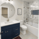 Elegant bathroom with marble shower, navy blue vanity, and modern fixtures.