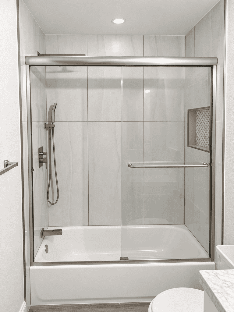 Contemporary glass shower with sliding doors and tiled walls.