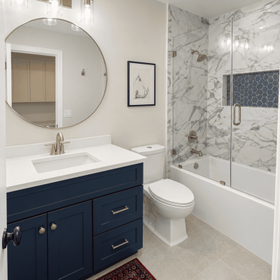 Elegant bathroom with marble shower, navy blue vanity, and modern fixtures.