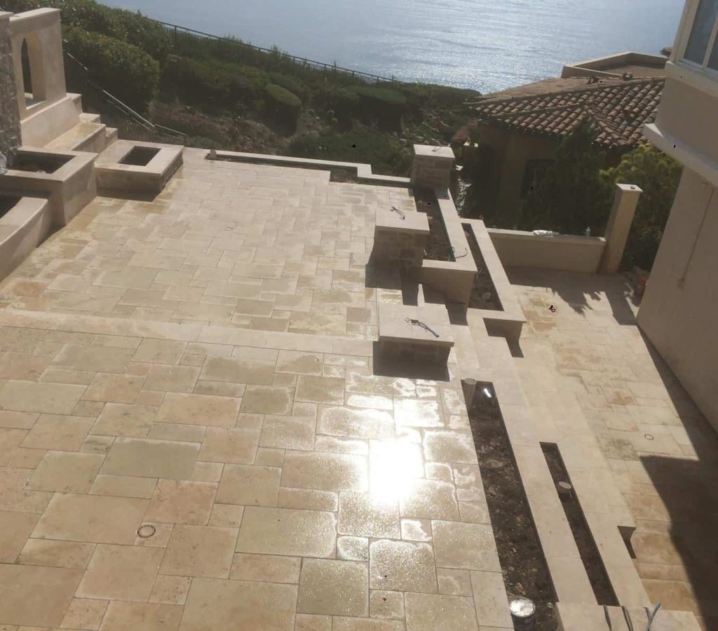 Beautiful outdoor patio with tile flooring and ocean view in the background.