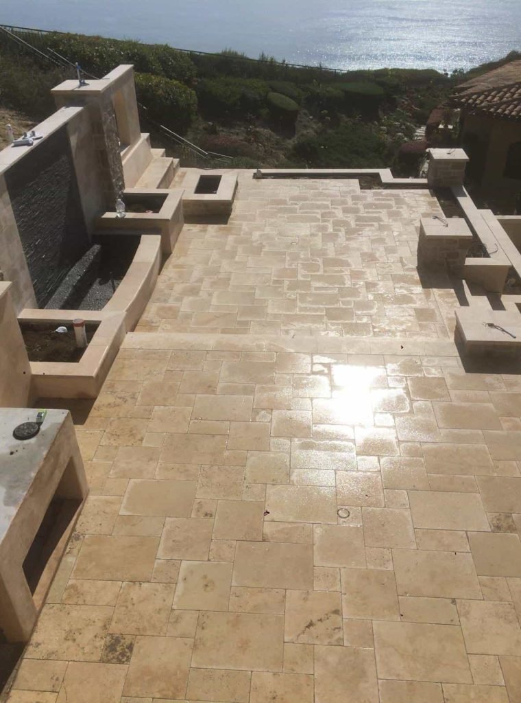 Elegant beige tile patio with water feature and ocean view in the background.