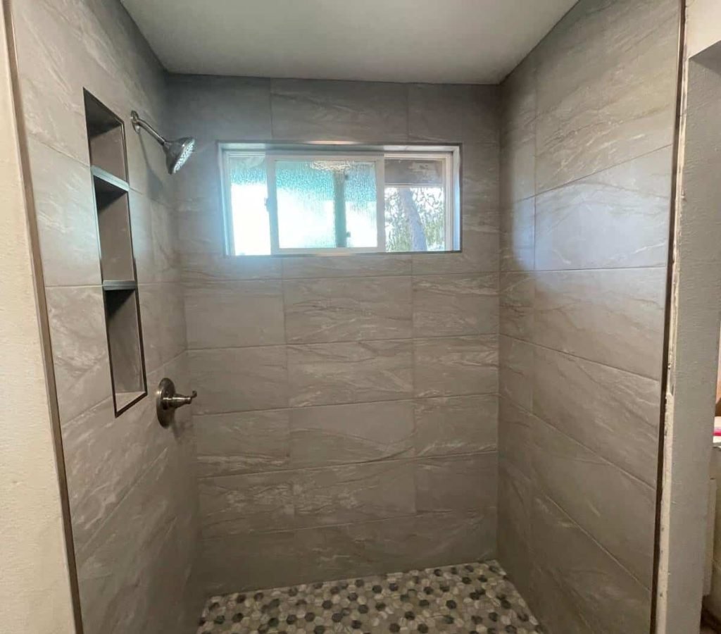 Modern tiled shower with pebble floor and built-in niche.
